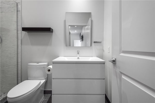 bathroom with tiled shower, vanity, and toilet