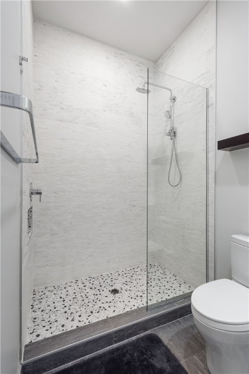 bathroom featuring tiled shower and toilet