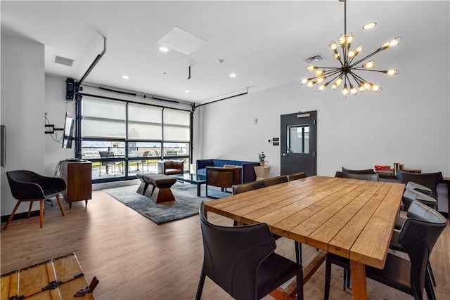 dining area with wood finished floors, plenty of natural light, a chandelier, and recessed lighting