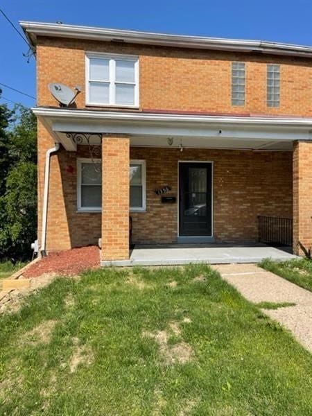 rear view of property featuring brick siding and a lawn