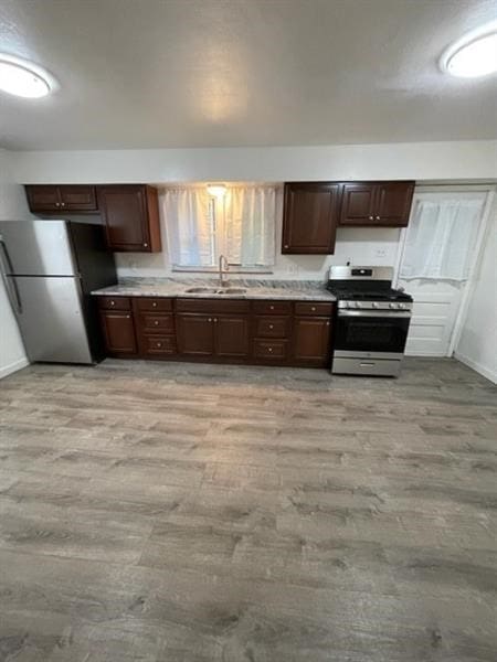 kitchen featuring light hardwood / wood-style flooring, sink, stainless steel appliances, and dark brown cabinetry