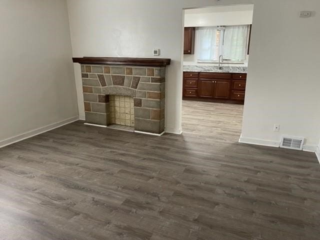 unfurnished living room with wood-type flooring and a brick fireplace