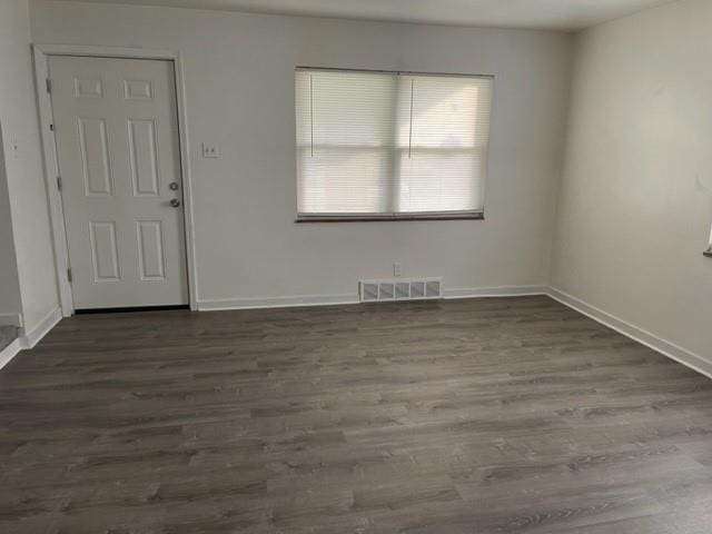 spare room featuring wood finished floors, visible vents, and baseboards