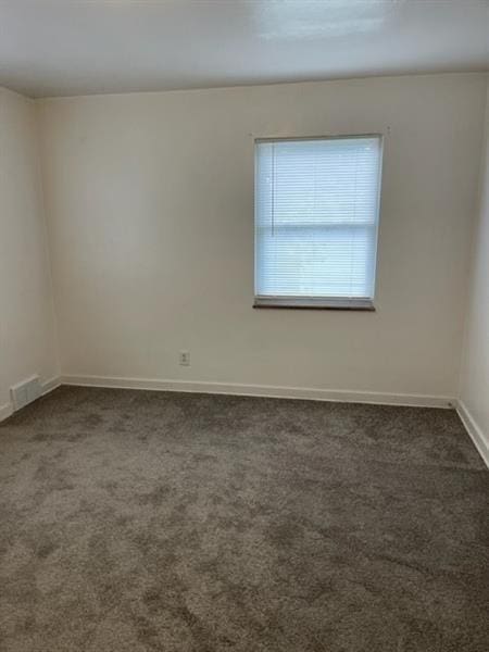 unfurnished room with dark colored carpet and baseboards