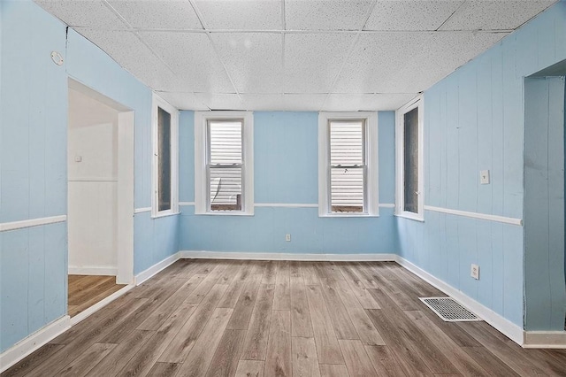 unfurnished room with a paneled ceiling and hardwood / wood-style flooring