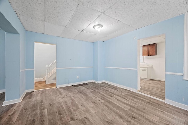 empty room with a paneled ceiling and light hardwood / wood-style floors