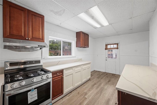 kitchen featuring light wood-type flooring, a paneled ceiling, and stainless steel gas range oven