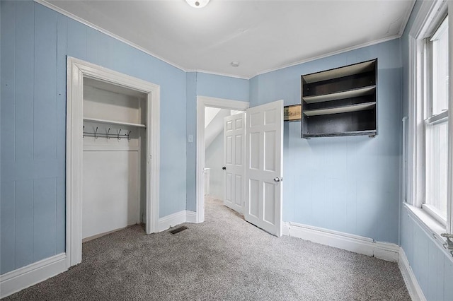 unfurnished bedroom featuring multiple windows, carpet floors, a closet, and ornamental molding