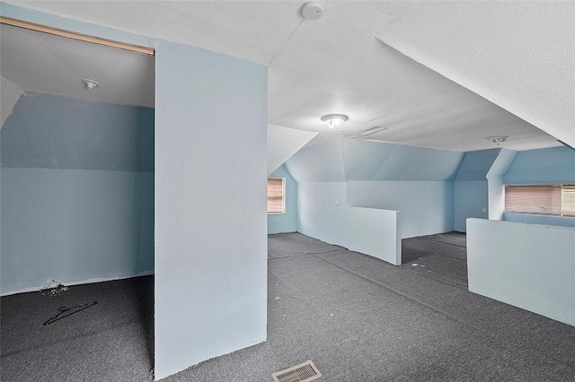 additional living space with dark colored carpet and lofted ceiling