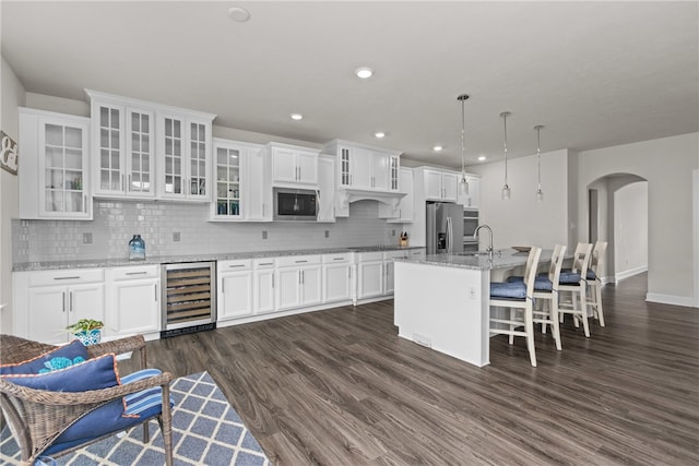 kitchen featuring appliances with stainless steel finishes, wine cooler, dark wood-type flooring, and decorative light fixtures