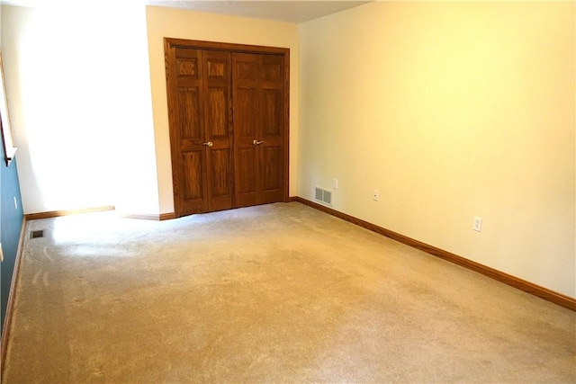 unfurnished bedroom with light colored carpet and a closet