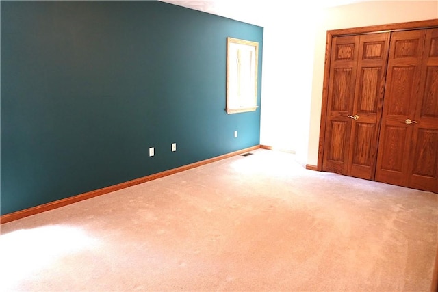 unfurnished bedroom with light colored carpet and a closet