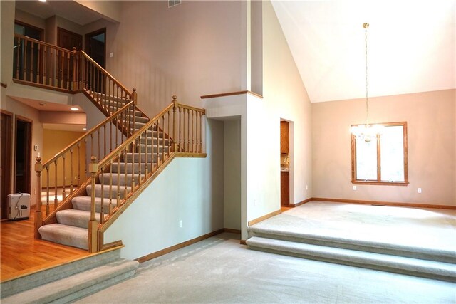 staircase with high vaulted ceiling, wood-type flooring, and a chandelier