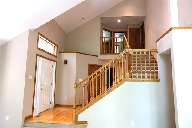 foyer entrance with wood-type flooring and high vaulted ceiling