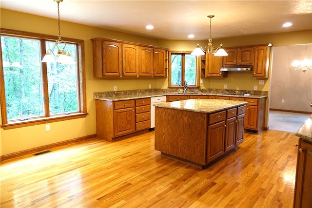 kitchen with a notable chandelier, light hardwood / wood-style flooring, hanging light fixtures, and a kitchen island