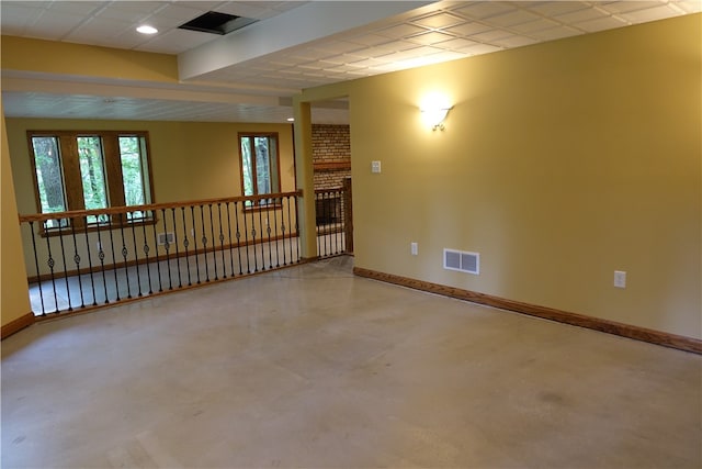 unfurnished room with concrete flooring, a fireplace, and a drop ceiling