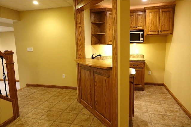 kitchen featuring a paneled ceiling, stainless steel microwave, sink, and light tile patterned flooring