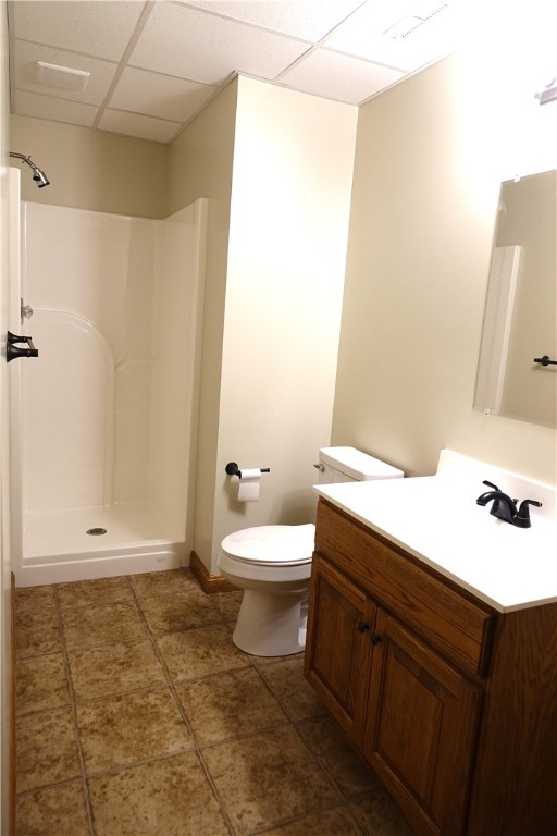 bathroom with a shower, toilet, tile patterned floors, vanity, and a paneled ceiling