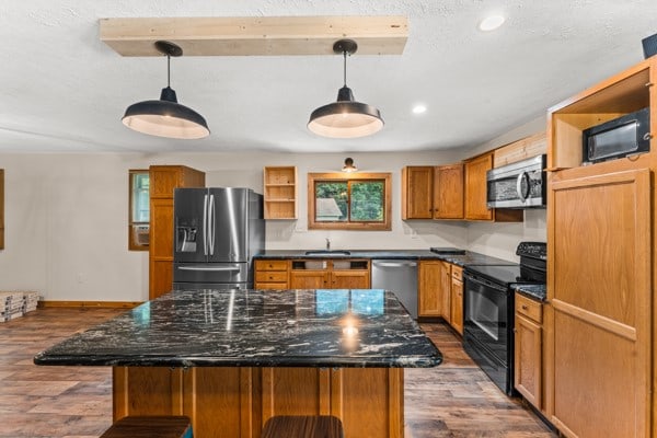 kitchen featuring black appliances, pendant lighting, a center island, and hardwood / wood-style flooring