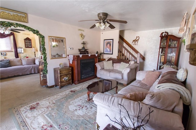 living area with a ceiling fan, stairs, a fireplace, and carpet flooring