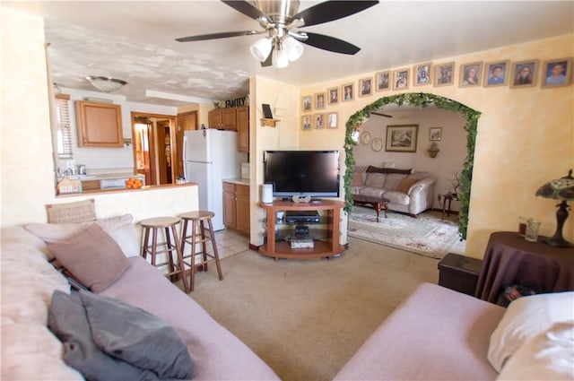 living area featuring light carpet and a ceiling fan