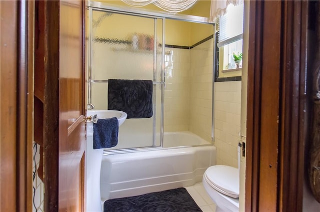 full bath featuring tile patterned floors, toilet, and shower / bath combination with glass door