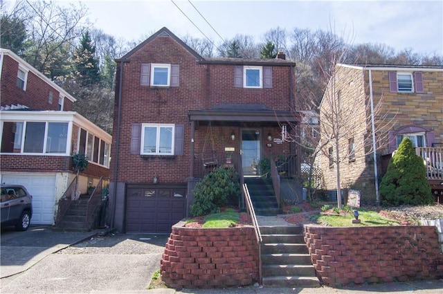 traditional-style house with stairway, an attached garage, brick siding, and driveway