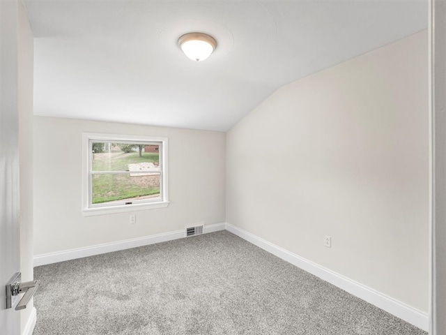 empty room with vaulted ceiling and carpet floors