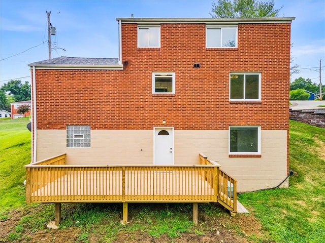 back of property with a wooden deck and a lawn