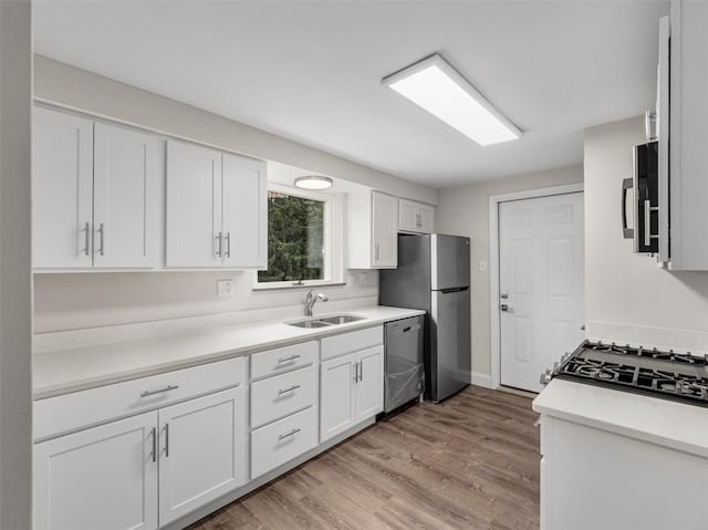 kitchen featuring appliances with stainless steel finishes, white cabinets, sink, and light hardwood / wood-style floors