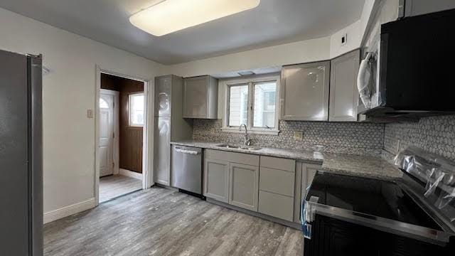 kitchen featuring decorative backsplash, sink, light hardwood / wood-style flooring, appliances with stainless steel finishes, and gray cabinetry