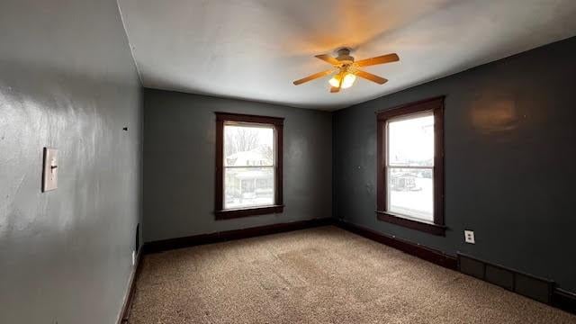 carpeted spare room with ceiling fan and plenty of natural light