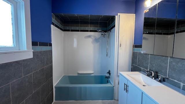 bathroom with bathtub / shower combination, tile walls, and vanity