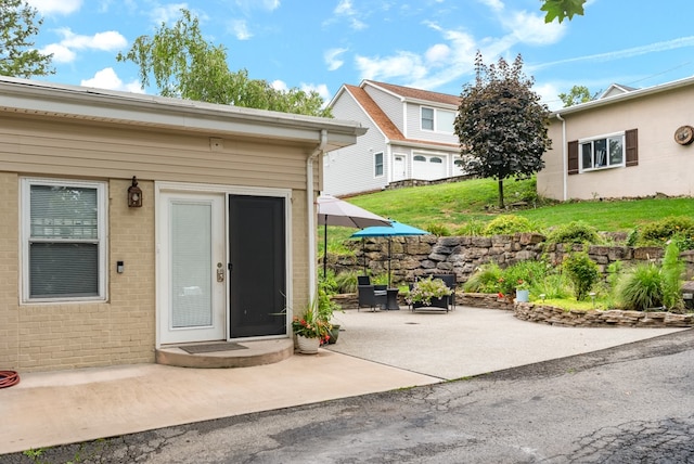 view of exterior entry with a lawn and a patio