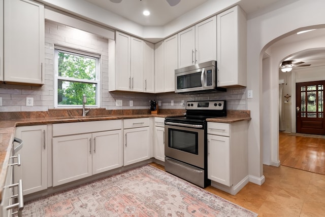 kitchen with light hardwood / wood-style flooring, stainless steel appliances, white cabinetry, ceiling fan, and sink