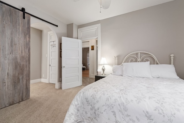 bedroom featuring a barn door and light carpet