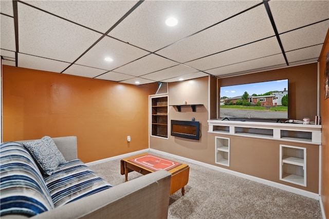 carpeted living room featuring built in shelves and a drop ceiling