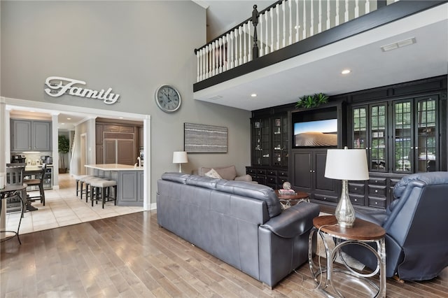 living room with a towering ceiling and light wood-type flooring