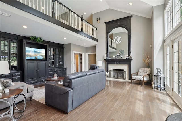 living room with wood-type flooring, a high ceiling, and ornamental molding