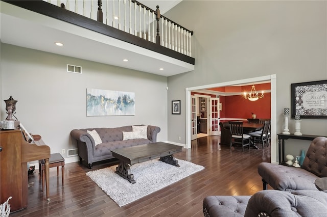 living room with dark hardwood / wood-style flooring, a chandelier, and a high ceiling