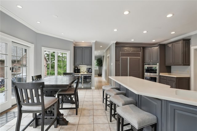 kitchen featuring double oven, crown molding, paneled built in fridge, beverage cooler, and light tile patterned floors