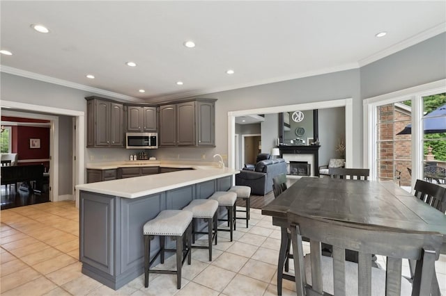 kitchen with stainless steel microwave, a peninsula, light countertops, a kitchen bar, and a fireplace