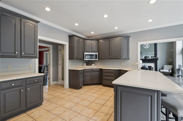 kitchen with kitchen peninsula, crown molding, gray cabinets, light tile patterned floors, and a breakfast bar area