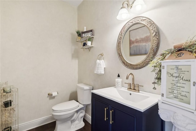 half bathroom with vanity, toilet, and baseboards