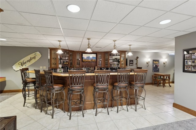 bar featuring light tile patterned floors and a paneled ceiling