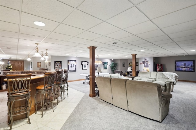 living room featuring decorative columns, a paneled ceiling, bar, and light carpet