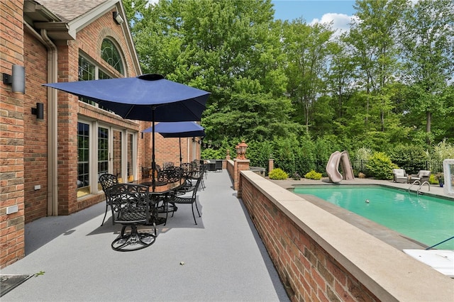 view of pool with a water slide and a patio area