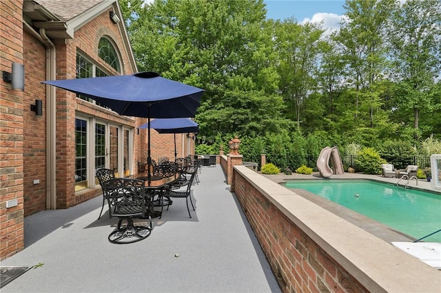 view of swimming pool with a water slide, a patio area, outdoor dining space, and a fenced in pool