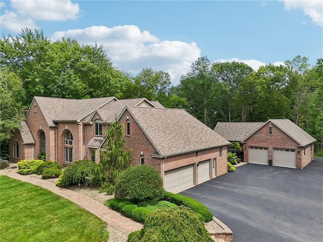 view of front facade with brick siding, roof with shingles, and a front yard