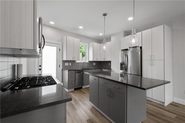 kitchen with gray cabinetry, pendant lighting, a center island, light hardwood / wood-style floors, and stainless steel appliances